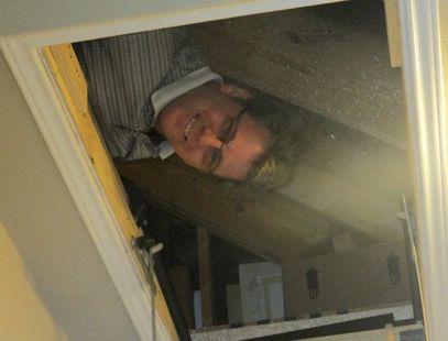 George Gibbons, owner of G2 Home Inspections, sticking head out of crawl space